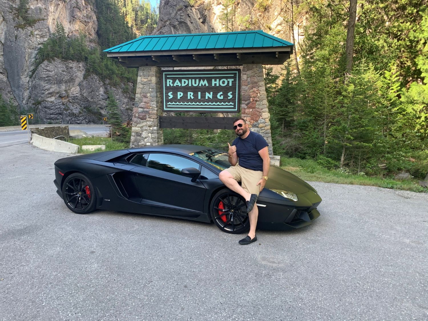 Danijel with a black Lamborghini at the Radium Hot Springs sign